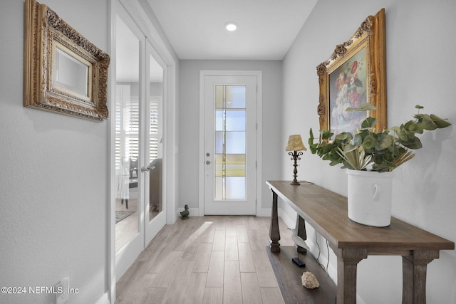 doorway to outside with a healthy amount of sunlight, light hardwood / wood-style flooring, and french doors