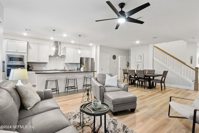 living room with ceiling fan, sink, and light wood-type flooring