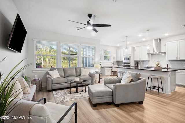 living room featuring ceiling fan, light hardwood / wood-style flooring, and sink