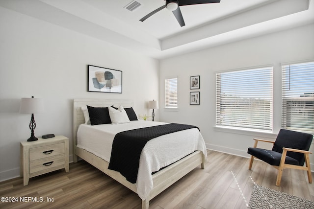 bedroom featuring a tray ceiling, ceiling fan, and hardwood / wood-style floors