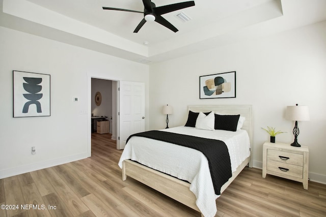 bedroom featuring hardwood / wood-style flooring, ceiling fan, and a raised ceiling