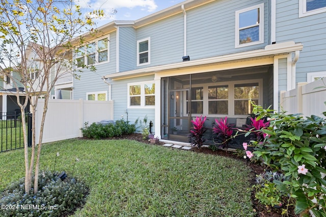 back of house with a yard and a sunroom