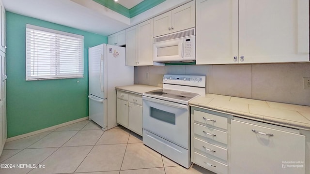 kitchen featuring tasteful backsplash, white cabinetry, light tile patterned flooring, and white appliances