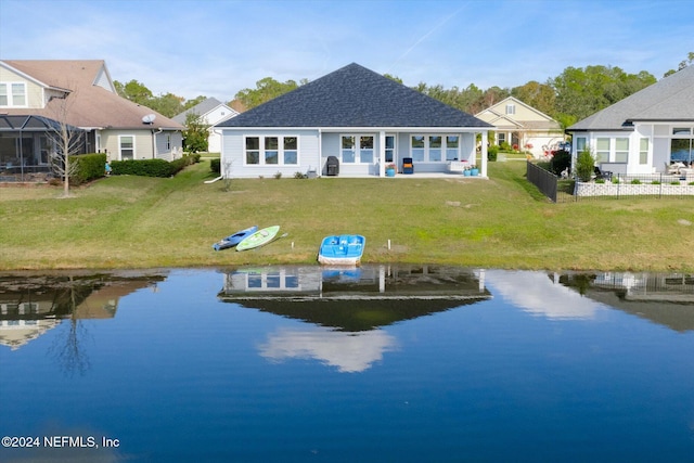 back of house with a lawn and a water view