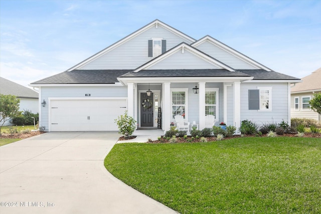 view of front of house featuring covered porch, a garage, and a front yard