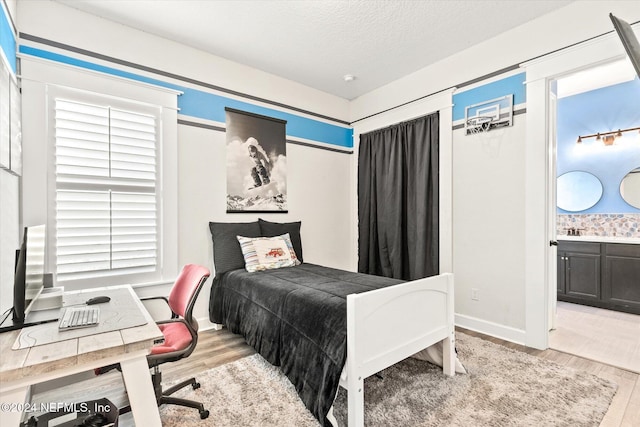 bedroom featuring sink, light wood-type flooring, and a textured ceiling