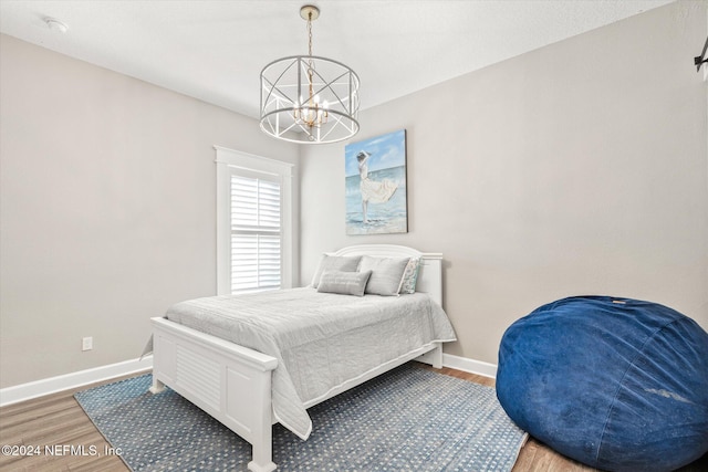 bedroom with hardwood / wood-style flooring and an inviting chandelier