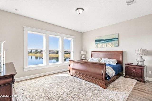 bedroom featuring hardwood / wood-style floors and a water view