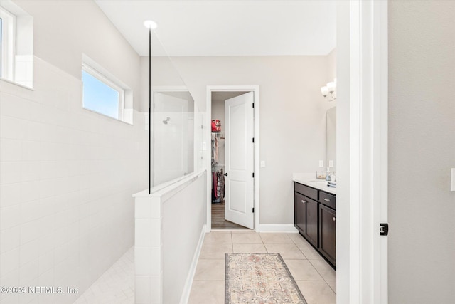 bathroom featuring a tile shower, tile patterned flooring, and vanity