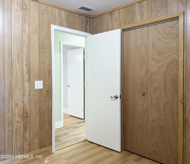 unfurnished bedroom with hardwood / wood-style floors, a textured ceiling, a closet, and wood walls