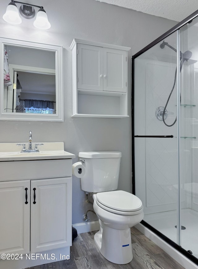 bathroom featuring a textured ceiling, toilet, vanity, a shower with shower door, and hardwood / wood-style flooring