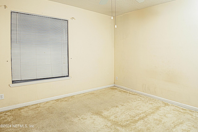 carpeted empty room with ceiling fan and a textured ceiling