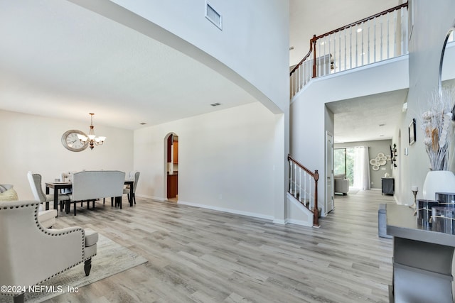 interior space with light hardwood / wood-style floors, a high ceiling, and a chandelier