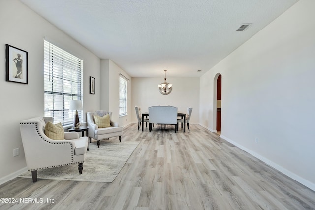 interior space featuring a textured ceiling, light wood-type flooring, and an inviting chandelier