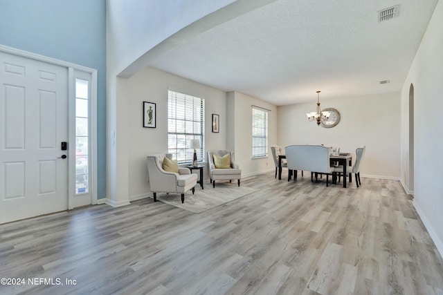 entryway featuring a textured ceiling, light hardwood / wood-style floors, and a notable chandelier