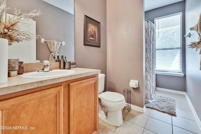 bathroom with tile patterned flooring, vanity, toilet, and a wealth of natural light