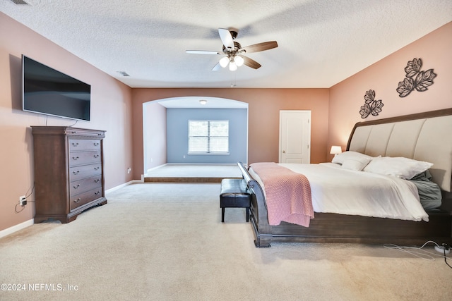 carpeted bedroom with ceiling fan and a textured ceiling