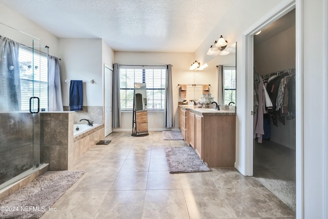 bathroom featuring plus walk in shower, plenty of natural light, vanity, and a textured ceiling