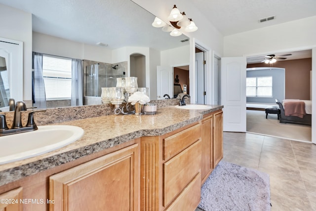 bathroom with a textured ceiling, ceiling fan, tiled shower, and vanity