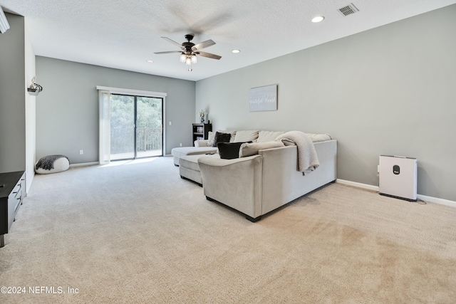 carpeted living room with ceiling fan and a textured ceiling