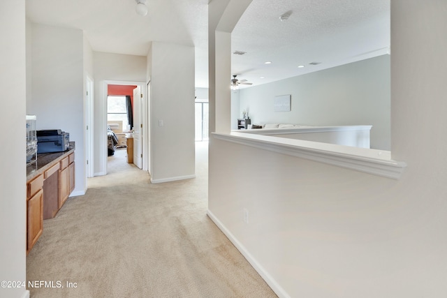 corridor with a textured ceiling and light colored carpet