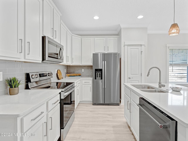 kitchen with hanging light fixtures, appliances with stainless steel finishes, white cabinetry, and sink