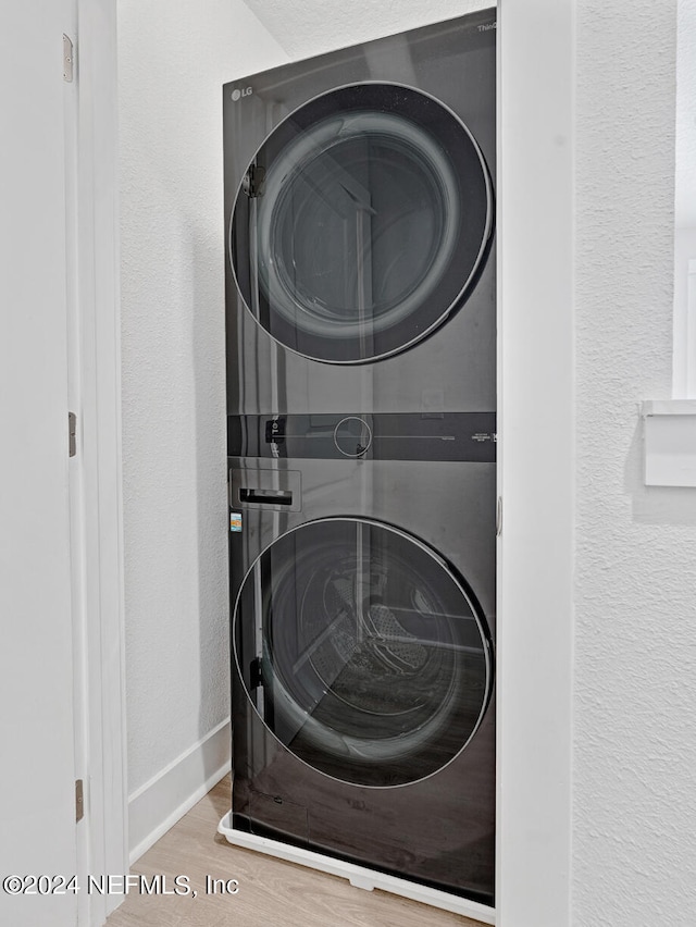 laundry area featuring hardwood / wood-style floors and stacked washer / dryer