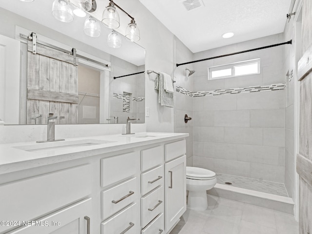 bathroom featuring vanity, tile patterned floors, toilet, tiled shower, and a textured ceiling