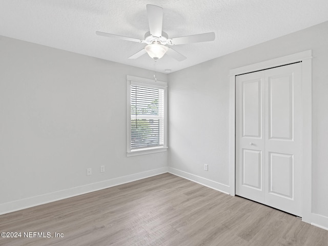 unfurnished bedroom featuring a textured ceiling, a closet, ceiling fan, and light hardwood / wood-style floors