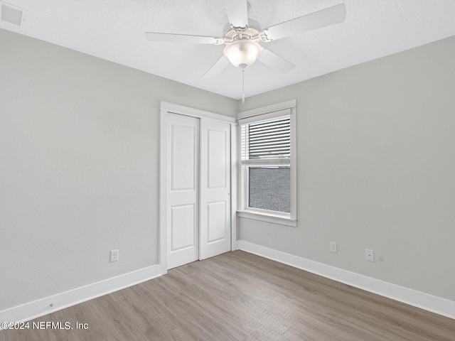 unfurnished bedroom with ceiling fan, a closet, and wood-type flooring