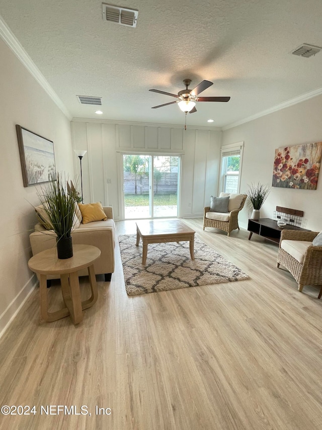 living room featuring ornamental molding, a textured ceiling, and light wood-type flooring