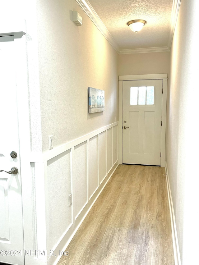 doorway to outside featuring light wood-type flooring, crown molding, and a textured ceiling