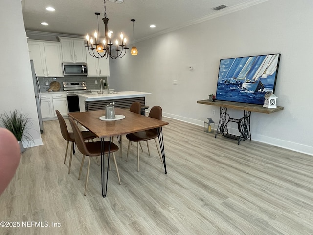 dining room featuring sink, crown molding, and light hardwood / wood-style flooring