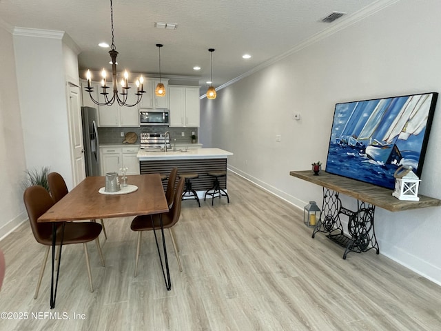 dining area with light hardwood / wood-style flooring, a textured ceiling, a chandelier, crown molding, and sink