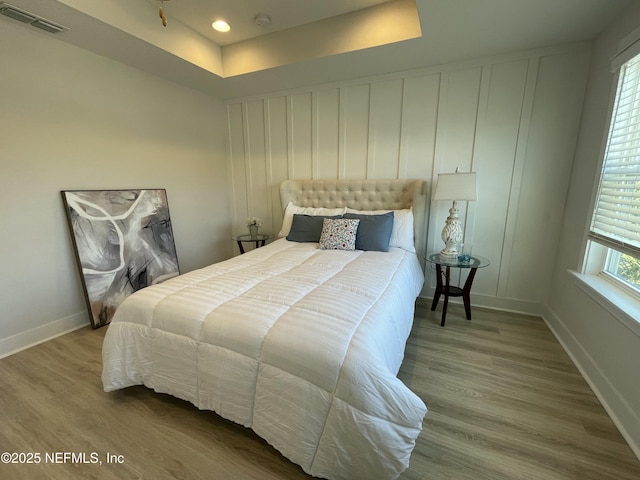 bedroom featuring a raised ceiling and hardwood / wood-style flooring