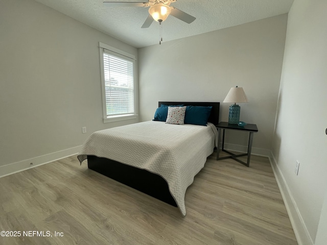 bedroom featuring ceiling fan, light hardwood / wood-style flooring, and a textured ceiling