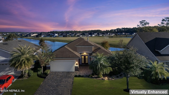 view of front of property with a lawn, a garage, and a water view