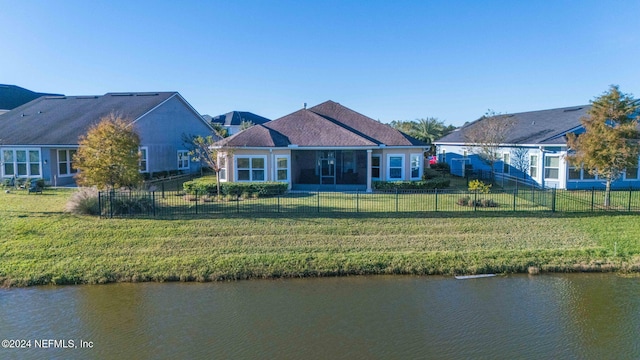 rear view of house featuring a water view and a yard