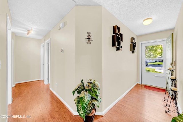 hall with hardwood / wood-style floors and a textured ceiling