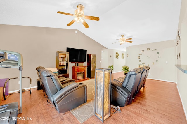 living room featuring ceiling fan, light wood-type flooring, lofted ceiling, and a fireplace