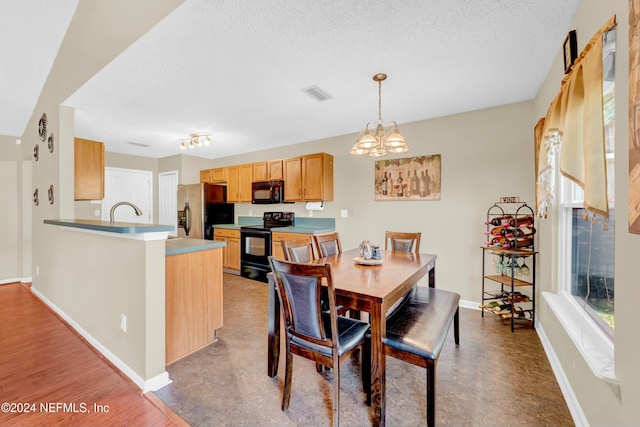 dining area featuring a notable chandelier, sink, and a textured ceiling