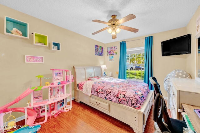 bedroom with ceiling fan, light hardwood / wood-style floors, and a textured ceiling