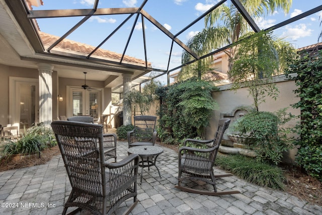 view of patio featuring ceiling fan, glass enclosure, and french doors