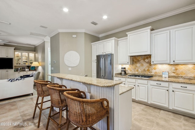 kitchen with light stone counters, white cabinets, stainless steel appliances, and ornamental molding