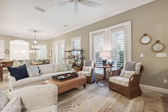 tiled living room with ceiling fan with notable chandelier and ornamental molding