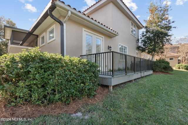 view of side of home featuring a yard and a wooden deck