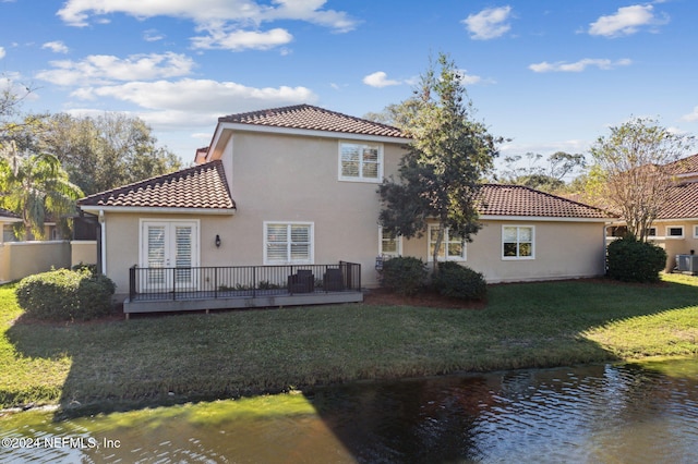 rear view of property featuring a lawn and a water view