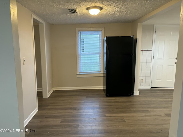 empty room with plenty of natural light, dark wood-type flooring, and a textured ceiling