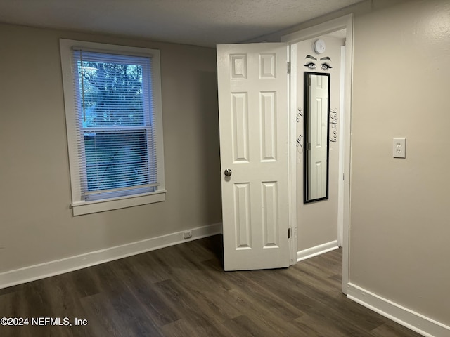 unfurnished bedroom with dark wood-type flooring and a textured ceiling