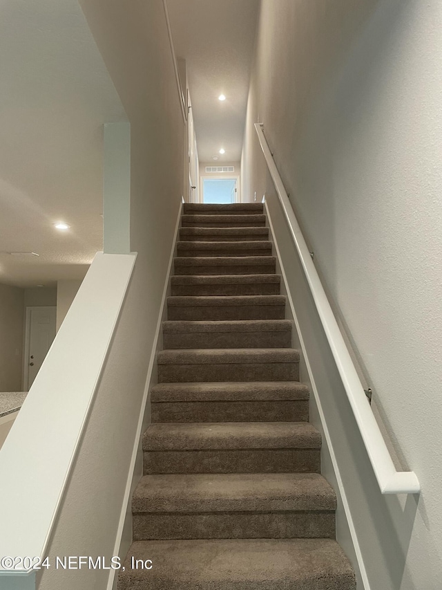 stairway featuring carpet flooring